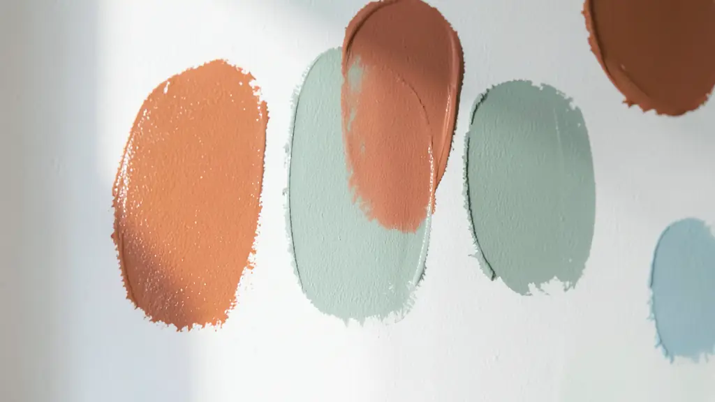 Close-up of several paint swatches on a white wall, different shades of terracotta and sage green, natural light hitting the surface, editorial photography